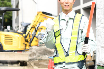 建設現場でガッツポーズをする交通誘導員