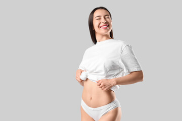 Fototapeta premium Happy young woman in stylish underpants and t-shirt posing on white background