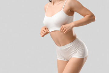Pretty young woman in stylish underwear posing on white background