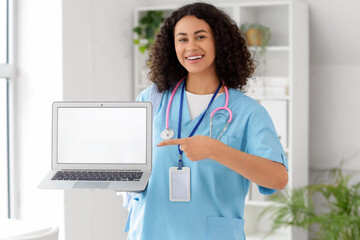 Female African-American medical student pointing at blank laptop in office