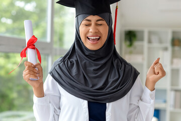 Happy female Muslim medical student with graduation hat and diploma at university