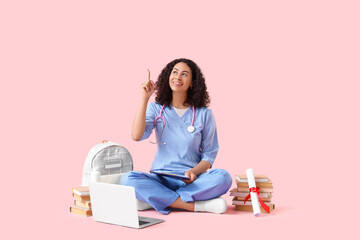 Female African-American medical student with clipboard pointing at something on pink background
