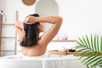 Pretty young woman taking bath at home