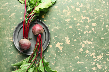 Plate with fresh beetroots on green grunge background