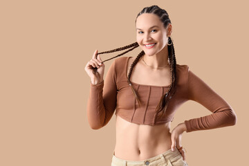 Stylish young woman with dreadlocks on beige background