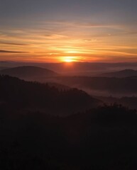 Fototapeta premium Intense dramatic lighting depicting sunset over misty Tuscan hills, high contrast, creating tension.