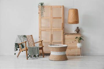 Interior of living room with wooden closet, armchair and table