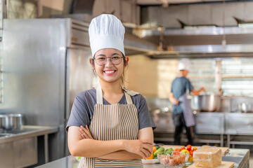 Young Female Chef Smiling in Professional Kitchen with Arms Crossed