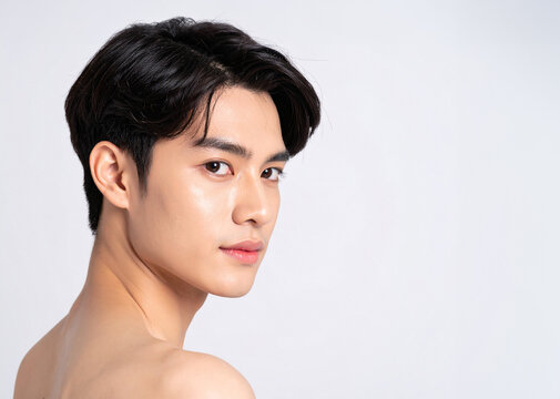 Close-up portrait of a young Asian man with clear glowing skin on white background
