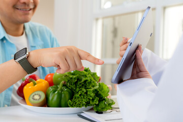 Asian nutritionist using tablet to explaining personalized meal plan with AI to patient during healthcare consultation, healthy lifestyle, woman dietitian showing nutrition plan with AI on tablet.