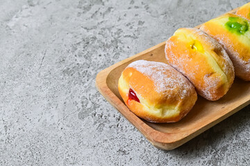 Close up view of four bomboloni doughnut with strawberry, pineapple and matcha filling on long...