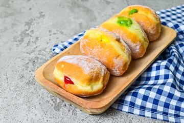 Extreme Close up view of four bomboloni doughnut with strawberry, pineapple and matcha filling on...