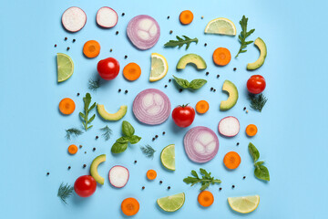 Different fresh vegetables with basil leaves, arugula and citrus fruits on blue background