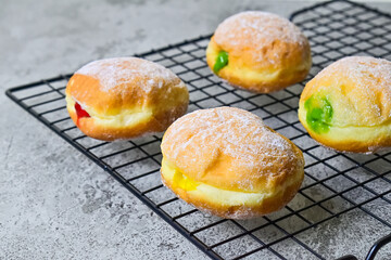 Close up view of four bomboloni doughnut with strawberry, pineapple and matcha filling on black...