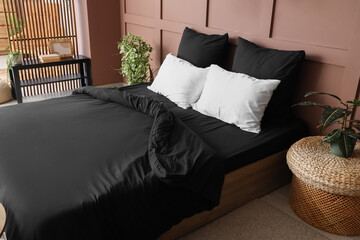 Interior of stylish bedroom with black linen and plants