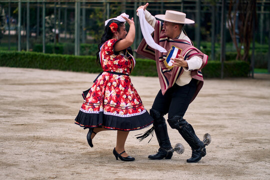 Portrait of a smiling young couple dressed as Chilean huasos,  joyfully dancing cueca outdoors. Traditional Chilean dance. Chilean traditions, celebrations.