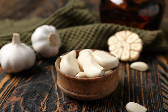 Bowl with fresh garlic cloves on wooden background, closeup