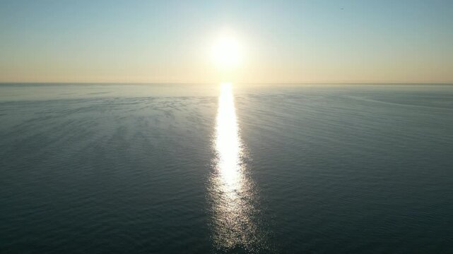 Seashore aerial: The Sun gracefully descends, casting a pathway of light across a serene ocean surface, evoking a sense of peace and vastness. Rimini, Emilia-Romagna