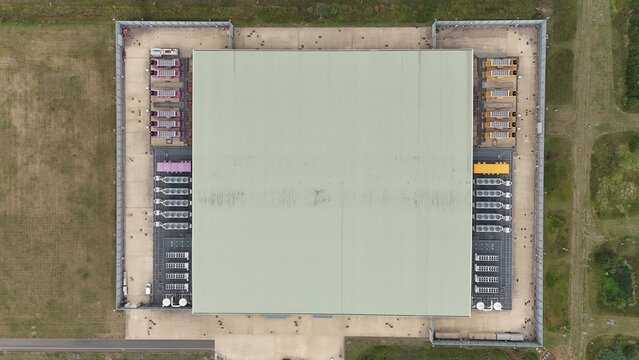 Aerial top down view of large futuristic cutting edge technology data center in England, with cooling fans and turbines, quantum computing and data storage.
