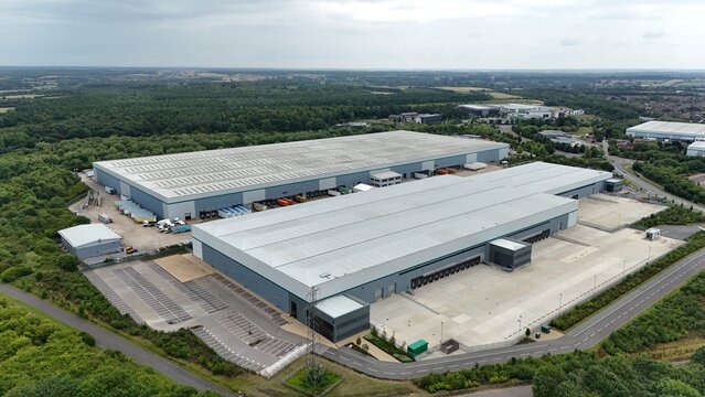 Aerial drone view of large distribution centers, warehouses, business park with heavy goods vehicles loading and unloading high value goods in England UK - Powered by Adobe