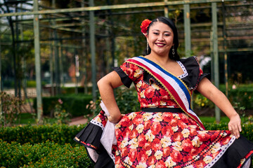 Portrait of a beautiful young woman smiling, cheerfully dressed as a Chilean huasa, joyfully...