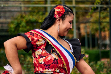Portrait of a beautiful young woman smiling, cheerfully dressed as a Chilean huasa, joyfully...