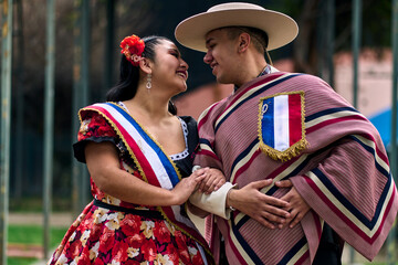 Portrait of a smiling young couple, dressed as Chilean huasos, looking at each other and posing...