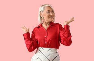 Beautiful mature woman dancing on pink background