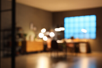 Blurred view of dark room with bookshelves, tables and glowing lamps at night