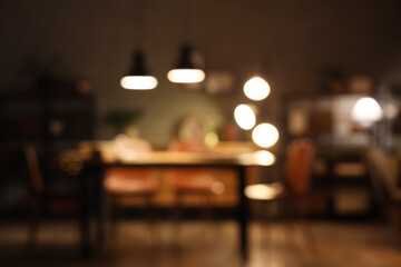 Interior of dark room with bookshelves, table and glowing lamps at night