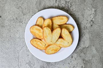 Top view of many mini pies on white plate isolated on grey or gray cement background. Love sign. High angle, above, close up. Danish. Pastry. Butter. Heart.