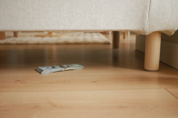 Cash hidden under the sofa in a living room setting, lost cash concept 