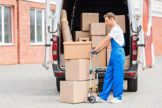 Male mover unloading boxes on trolley outdoors