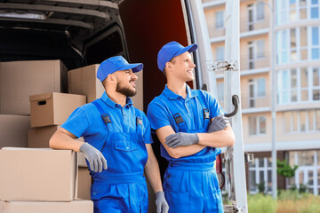 Male movers with boxes near car on street