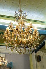 Elegant classic chandelier with warm lighting in colonial-style building. Ideal for vintage decor, antique interior, or luxury ambiance themes.
