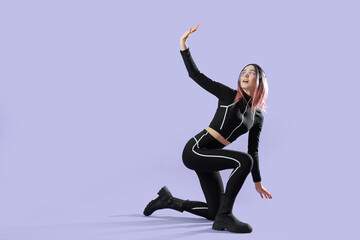 Young woman in futuristic costume with VR glasses on lilac background