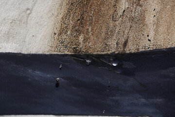 The white wall was soiled by water seepage, the path left a brownish trail and several drops of water were visible falling from the puddles that had arisen due to the seepage