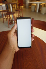 Hand holding a smartphone at a modern cafe table