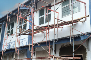 Several scaffolds with some wood and bamboo installed in front of a building that is being renovated, the wood and bamboo are steps for the builders