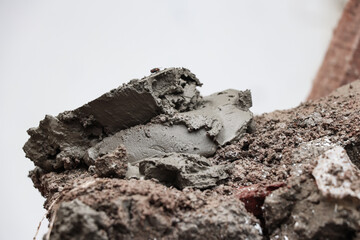 A pile of wet cement mixture on top of the remaining chunks of the building wall, a fly can be seen...