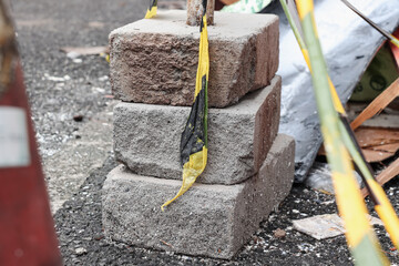 Three white bricks stacked on the asphalt, a safety line is visible around them and in the background there are the remains of a building