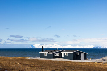 Beautiful landscape with of a cottage along the coast with snowy mountains near Longyearbyen in the arctic of Svalbard, Norway
