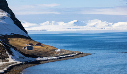 Beautiful landscape with of huts along the coast with snowy mountains near Longyearbyen in the...