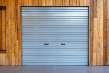Modern roller door set within a timber-clad facade in a retail or community space. A lockable shop or a small convenience store, providing security to an open space.