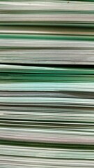 A stack of mint green paper awaits, each sheet ready to be transformed into a work of art, seen up close