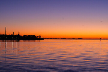 Naklejka premium Ferry dock in Geelong for the Spirit of Tasmania with industrial cranes in the background as the sun sets over the Bass Strait in Victoria, Australia
