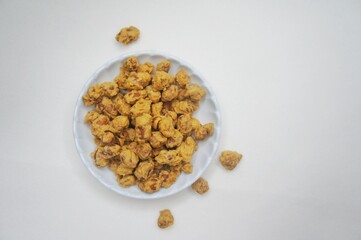 Close-up of egg bean snack (Camilan kacang Telur,Kacang Medan) in a small white plate on a white background. High angle view