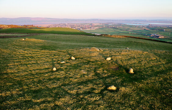 Stone circle known as Lacra 2 in prehistoric landscape on fellside above Millom on Irish Sea coast, Cumbria. View SE. Evening light
