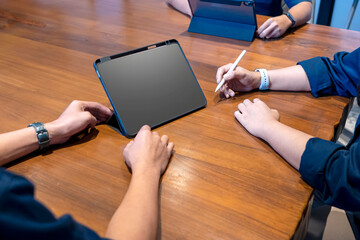 Group of business people meeting using a digital tablet device on a wooden table. Mockup or copy space. Concept of teamwork