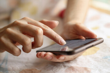 スマホを操作する女性の手元　A close-up of a woman's hands operating a smartphone　Generative AI